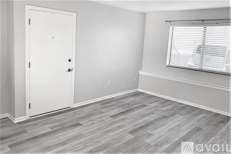 Living room showing entry door and window with view of parking area.