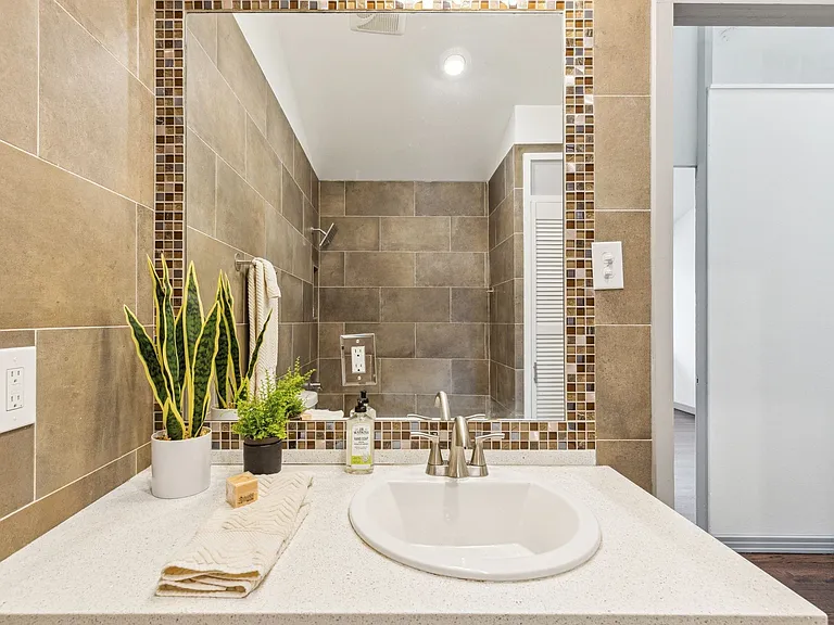 Bathroom vanity featuring a solid surface countertop with integrated oval sink and brushed nickel faucet