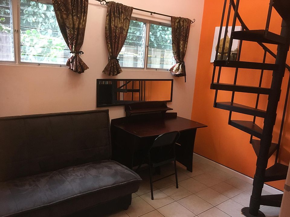 Futon couch, desk area & stairs leading up to loft bedroom