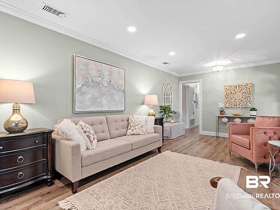 Spacious living area featuring light wood-finish flooring, recessed lighting, crown molding, and a neutral wall color