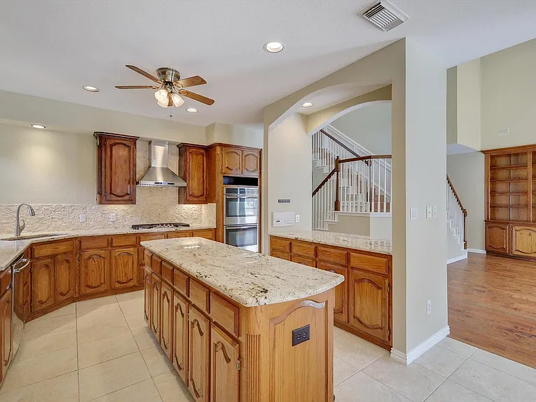 Kitchen featuring a central island with a granite countertop, wood cabinetry, built-in stainless steel appliances, and tile flooring
