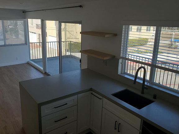 Black sink and faucet, floating shelves, waterfall peninsula.