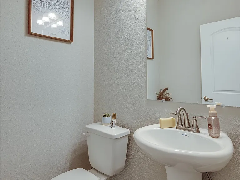 Pedestal sink with brushed nickel faucet, large mirror, and four-light vanity fixture