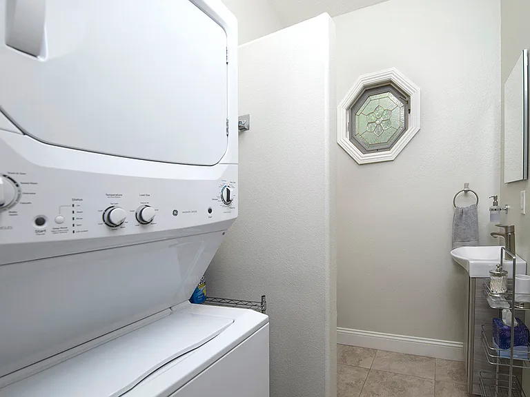 In suite full laundry with a full capacity stacked washer & dryer. There is also an additional toilet and vanity sink with cabinet for storage.