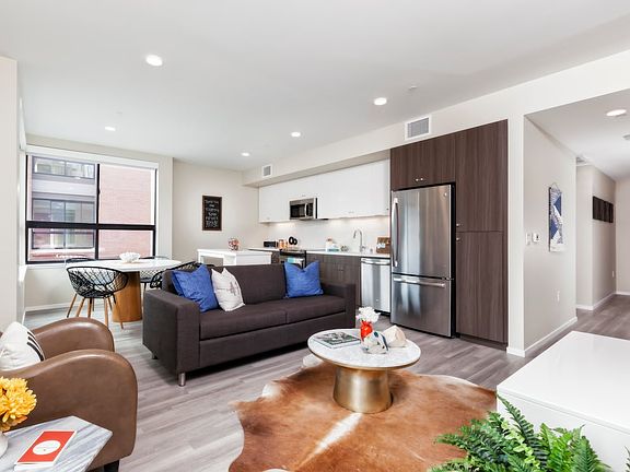Living and dining area with hard surface flooring and open concept kitchen with stainless steel appliances