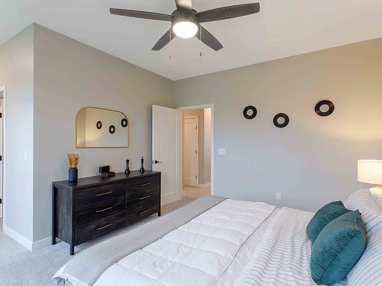 Elegant bedroom featuring a cozy bed with plush pillows, a sleek dresser with decorative accents, and soft neutral tones complemented by modern lighting.