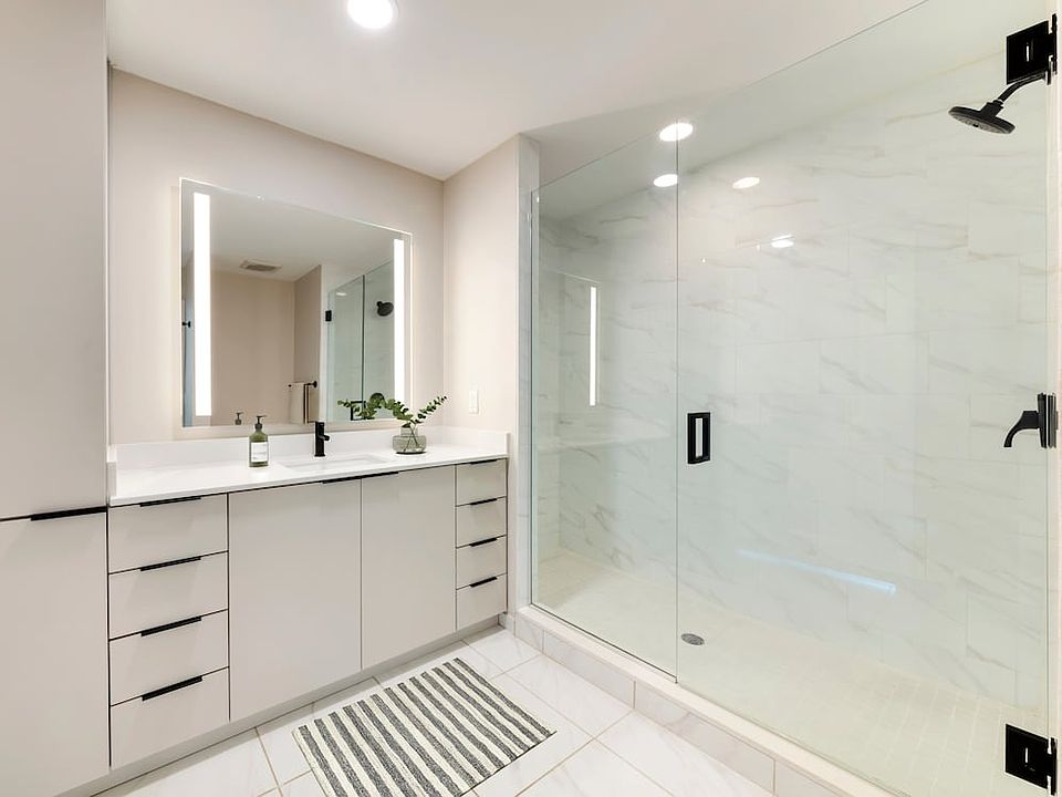 Tower Building - Renovated bath with white quartz countertop, light grey cabinetry, and tile flooring