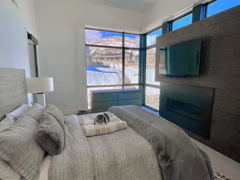 Master bedroom, gas fireplace with mounted tv above and motorized shades. Furniture from RH gallery.