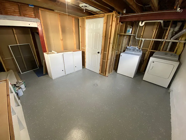 Spacious laundry room with washer and dryer, fresh painted floor, and ample storage space. Spacious laundry room with washer and dryer, fresh painted floor, and ample storage space.
