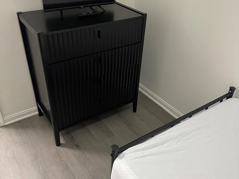 Furnished bedroom setup featuring a bed, dresser with TV, and durable flooring for easy everyday living.