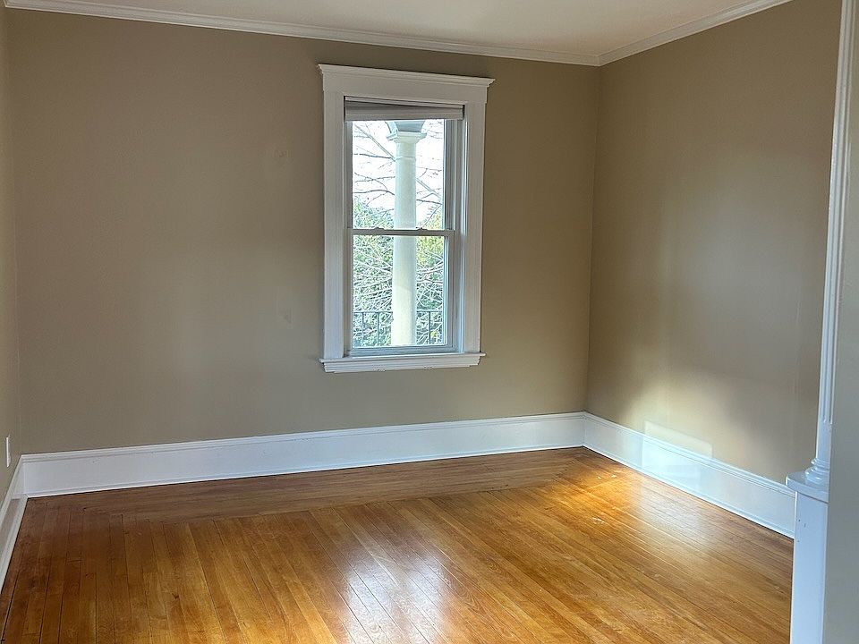Sun-filled living room with hardwood floors and built-in cabinet.