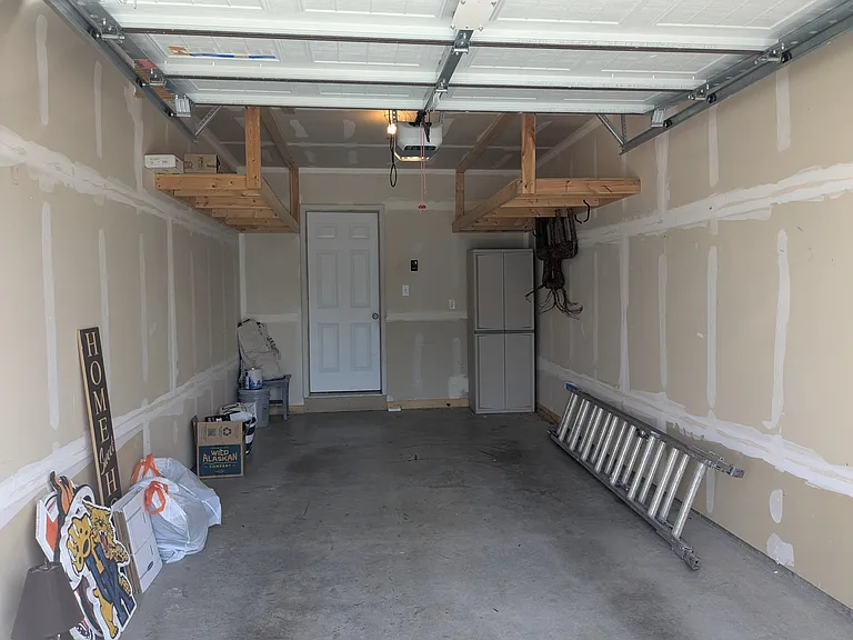 One car garage with additional wooden storage shelves up top.