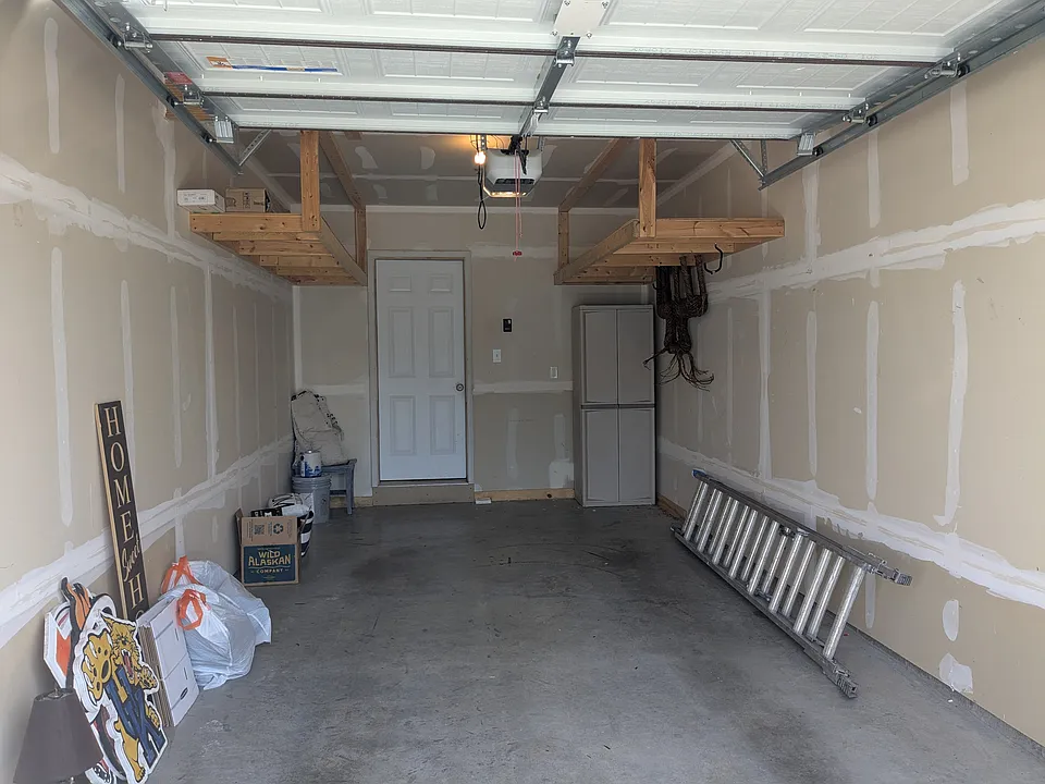 One car garage with additional wooden storage shelves up top.