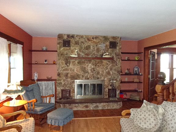 Stone fireplace in living room. To the right is the formal dining room.
