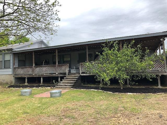 Front Exterior of the home. HUGE wrap around porch, and fruit trees.