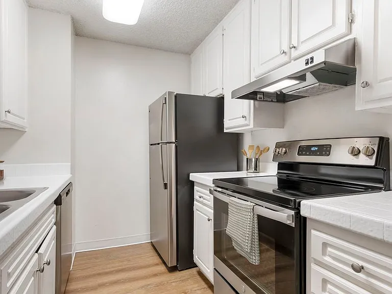 Classic Package II kitchen with stainless steel appliances, white tile countertops, white cabinetry, and hard surface flooring