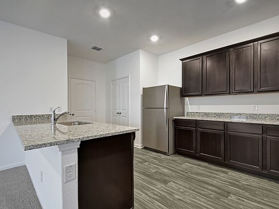 The kitchen features granite countertops and stunning wood cabinetry