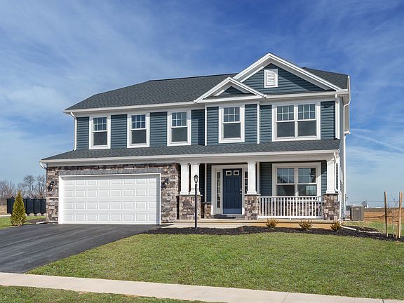 Two-story blue home with stone accents, white trim, covered front porch, and two-car garage