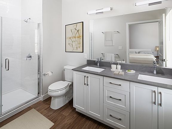 Phase II Renovated Package I townhome bath with grey quartz countertops, white cabinetry, and hard surface flooring