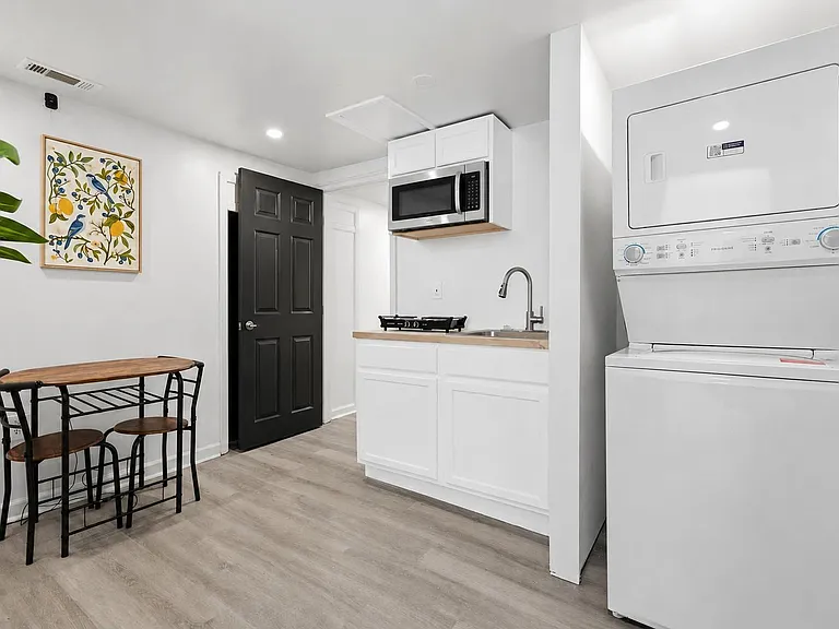 Efficient kitchenette with sink, microwave, and cooktop, plus a small dining set and in-unit stacked laundry for convenience.