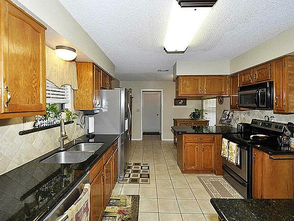 A spacious kitchen with granite counters and ceramic tile flooring