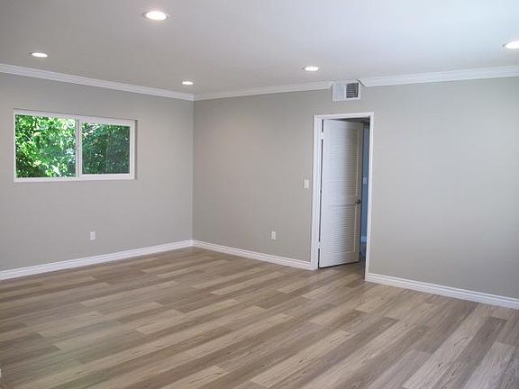 Living room with new flooring, paint, recessed lights, and crown moldings.
