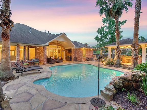 Recently refinished pool decking, large covered back porch, lush landscaping, and appealing summer kitchen.