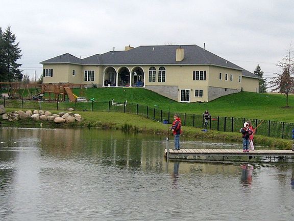 Back side of house with pond and playground and kids fishing