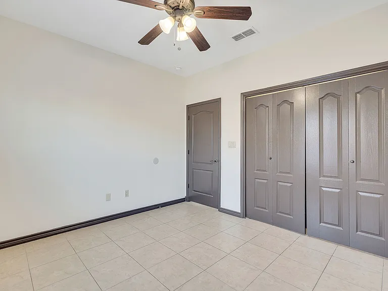 Interior of a room at Merida Vista Apartments in Laredo, Texas, with two closets and a ceiling fan visible