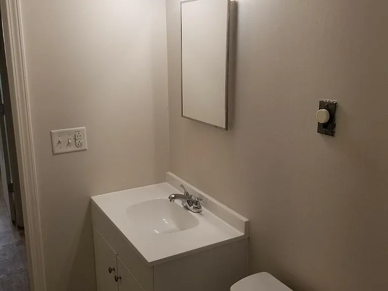 Single bathroom vanity with above mirror lighting.