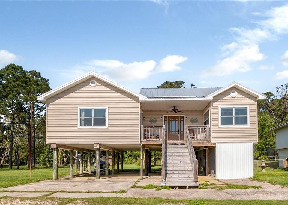 Rear view of house with a carport, stairway, driveway, ceiling fan, and metal roof