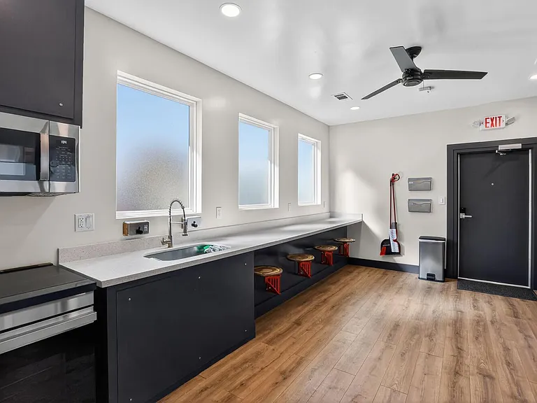Eat-in kitchen with long prep counter, undermount sink, stainless microwave, and bar seating beneath oversized windows.