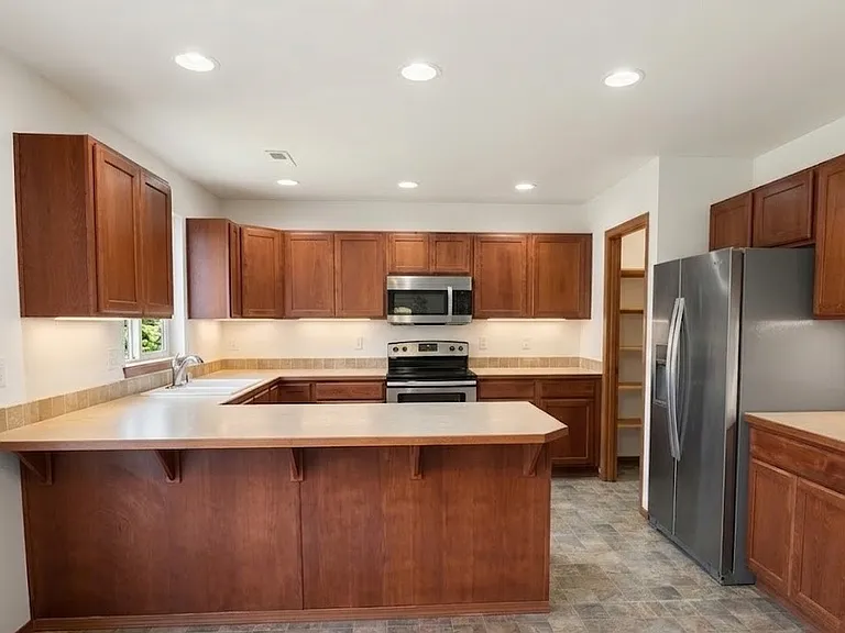 Open kitchen with breakfast bar, stainless steel appliances and large walk-in pantry.