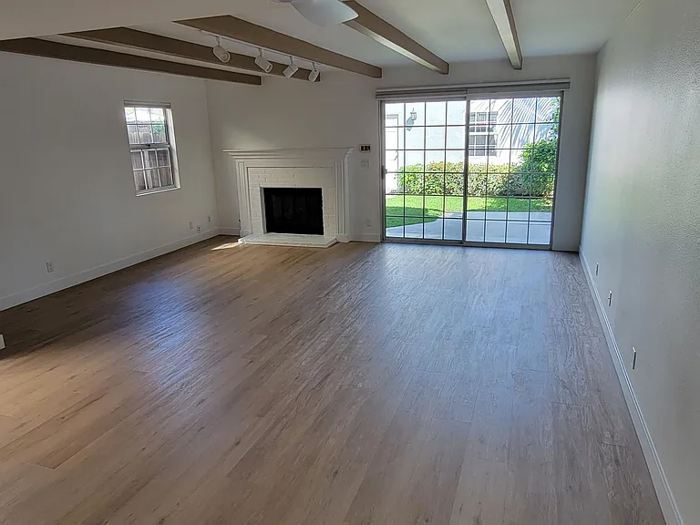 Family room with new flooring, tract lighting and fireplace.