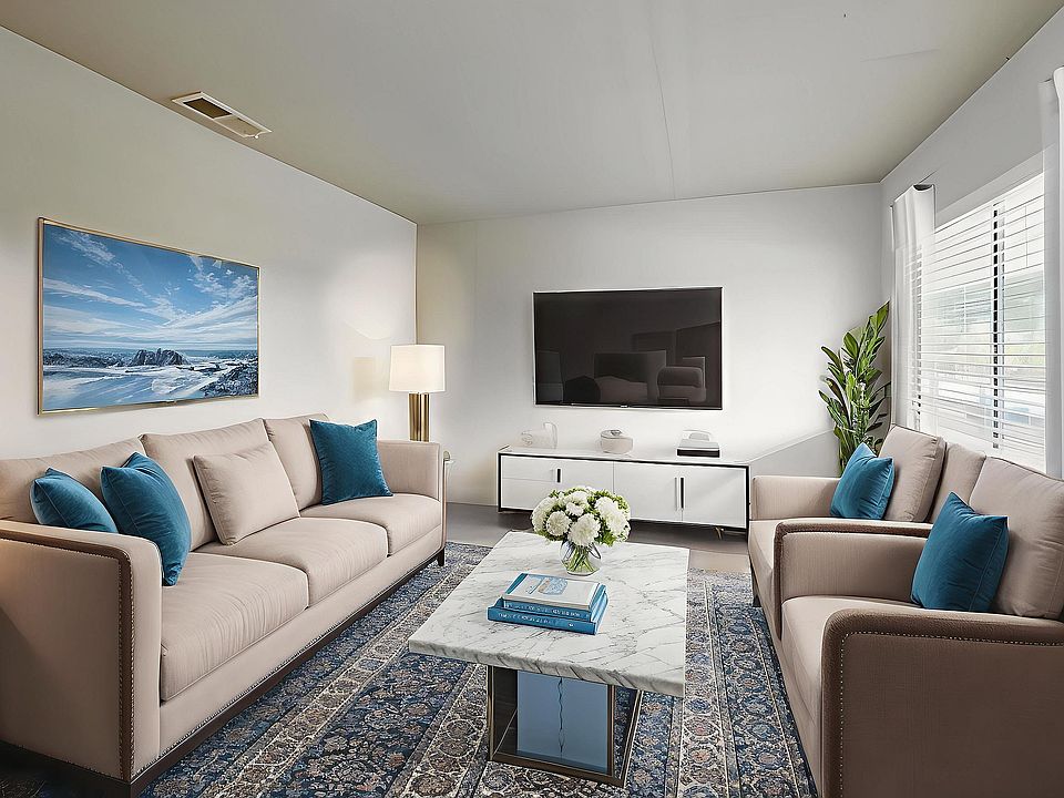 Chic modern living room with plush beige sofas, vibrant blue cushions, and a sleek marble coffee table. Elegant decor featuring stylish plants, artistic wall painting, and ample natural light.