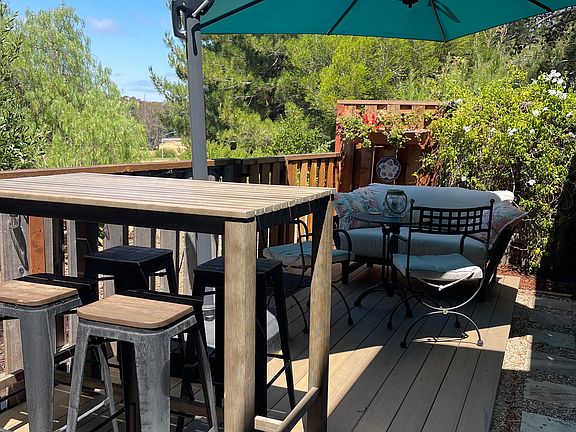 Outdoor deck with bar height table and chairs, sitting area, cantilever sun umbrella.