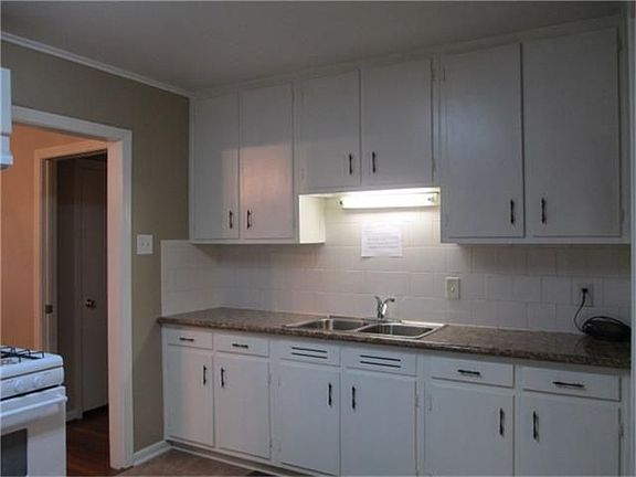 The kitchen glistens with granite counter tops and a wall of storage.