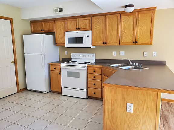 Tiled Floor Kitchen area with all appliances - range, microwave, dishwasher and refrigerator. Large peninsula work area with extended bar top area for seating.