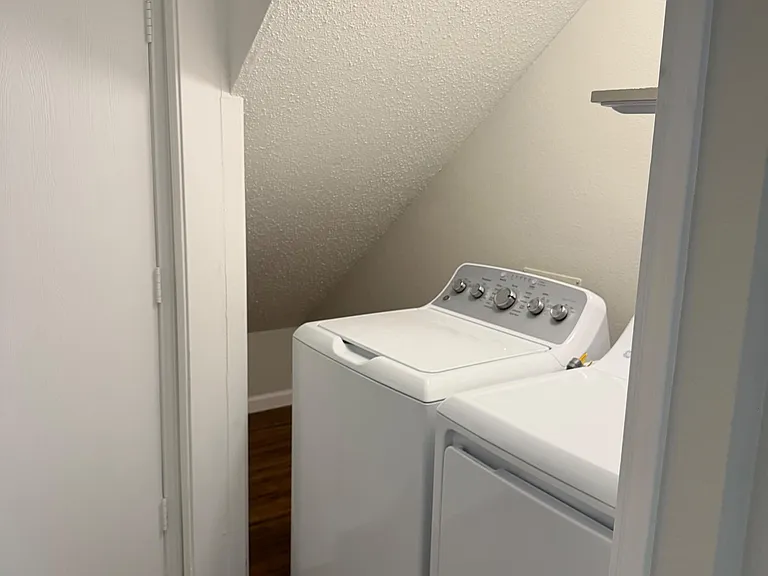Compact laundry nook with side-by-side washer and dryer tucked under the stairs for convenient in-home laundry.