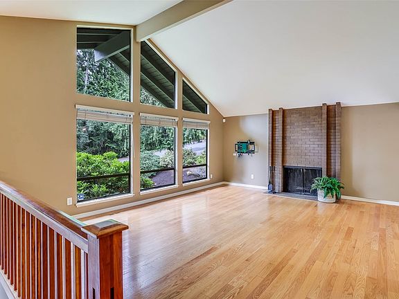 Enjoy the spacious living room with floor to ceiling windows, gleaming hardwood floors and brick-faced fireplace.>