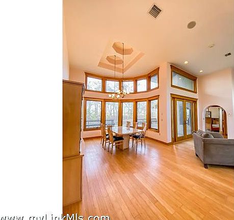 Looking at dining area from front entryway. Double glass doors to the right open to the back deck