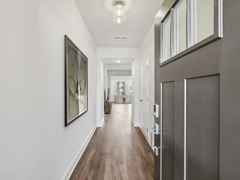 The entrance to the Stafford home featuring rich hardwood-style flooring and crisp white walls.