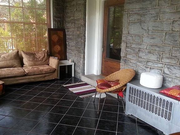 Tiled sun porch with stone wall.