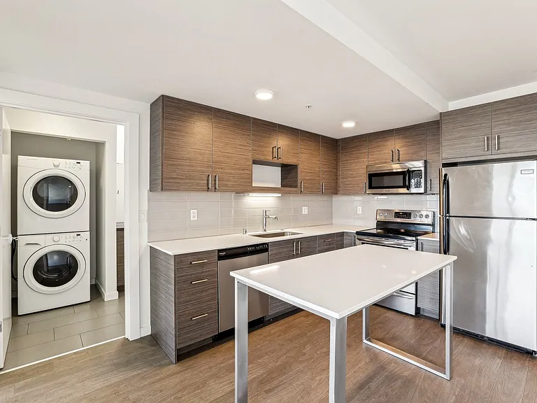 Experience modern living in this stunning kitchen at 4400 Alaska in Seattle, WA, featuring stainless steel appliances, a spacious island, and convenient in-u...