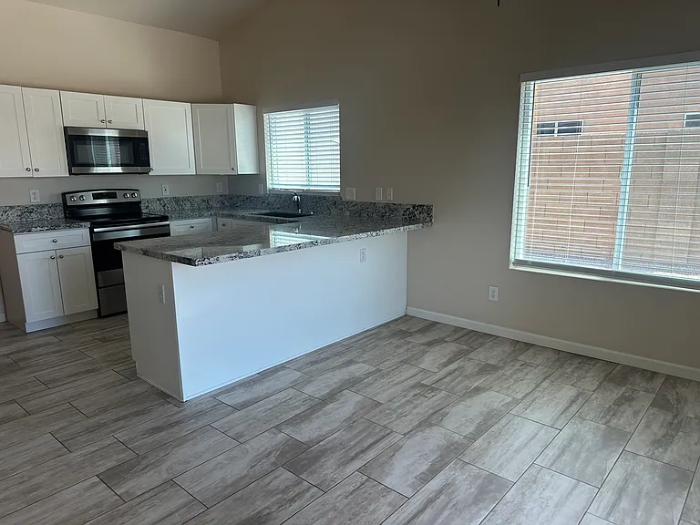 The kitchen boasts white shaker cabinetry with granite countertops. Newer stainless steel oven, built-in microwave, and dishwasher.