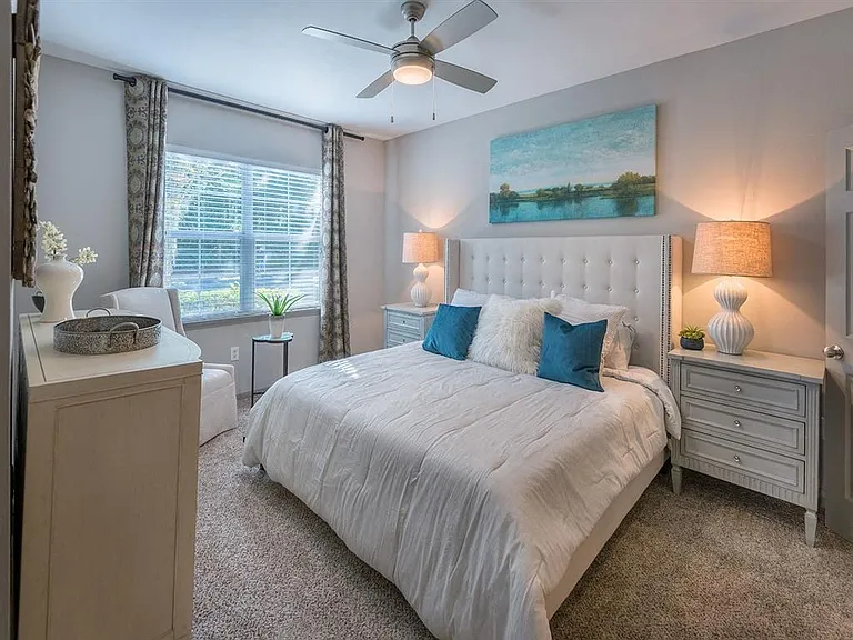Bedroom with a large window, carpeted flooring and ceiling fan