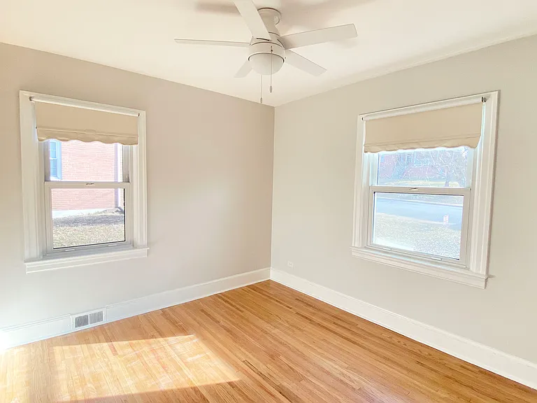 Bedroom 1 with two windows, hardwood floors and ceiling fan