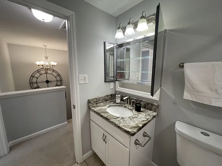 Hall bath with high end medicine cabinet with mirrors throughout and bright lighting