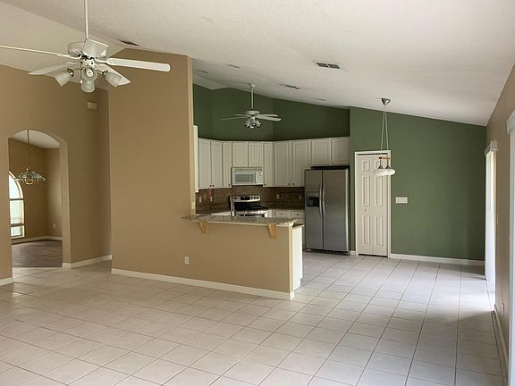Large open family area with high vaulted ceilings flows into breakfast nook and open kitchen.