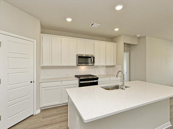 This kitchen features linen-colored cabinets and quartz countertops.